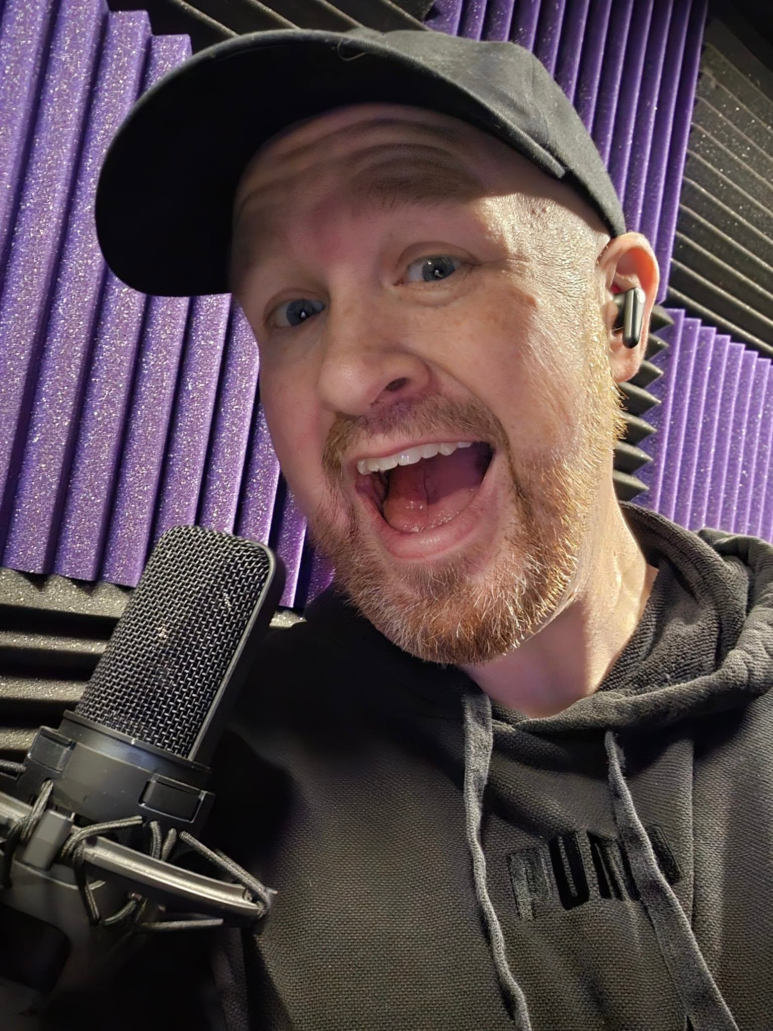 Brady Flanagan recording beside a microphone in a treated voice booth